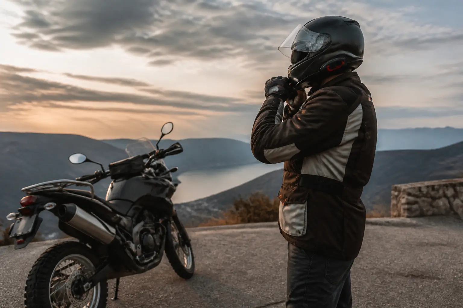 Motorcyclist checking protective gear before riding at dusk
