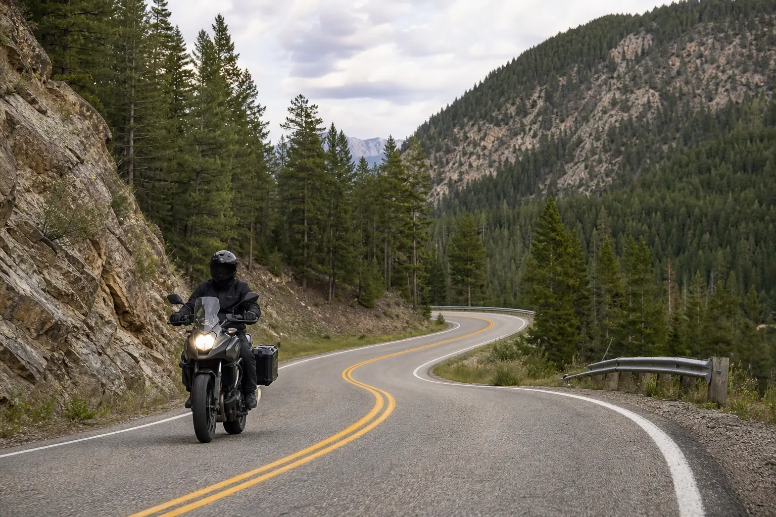 Motorcyclist approaching a tightening curve on a forest road.
