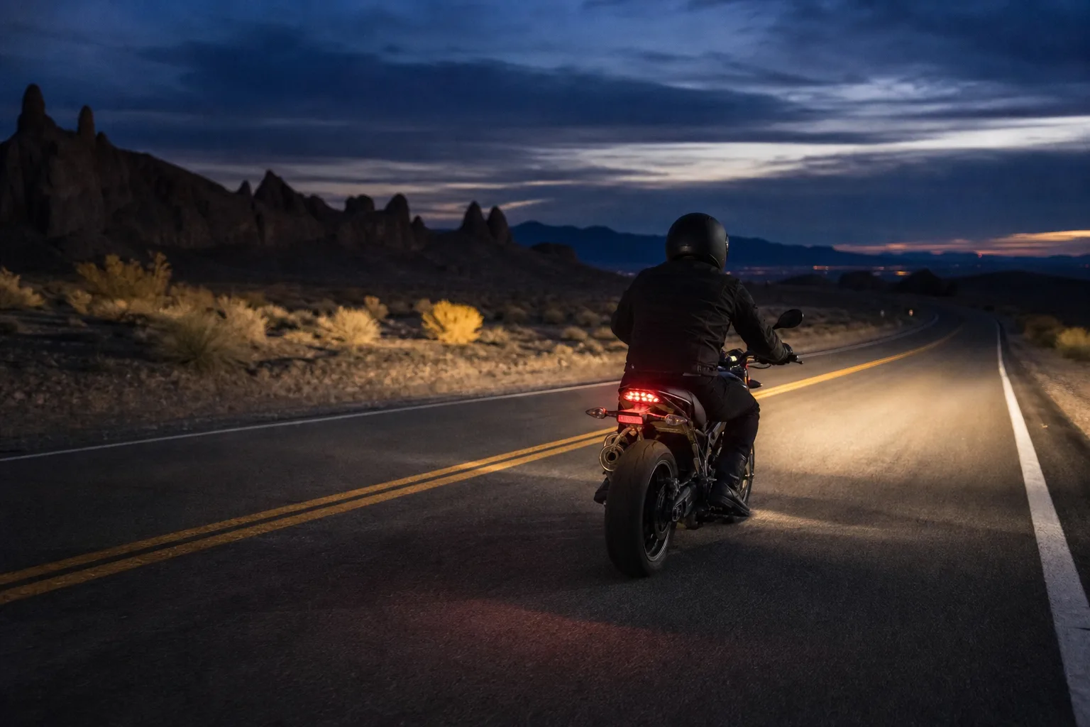 Motorcycle riding at night with controlled illumination on the road ahead.