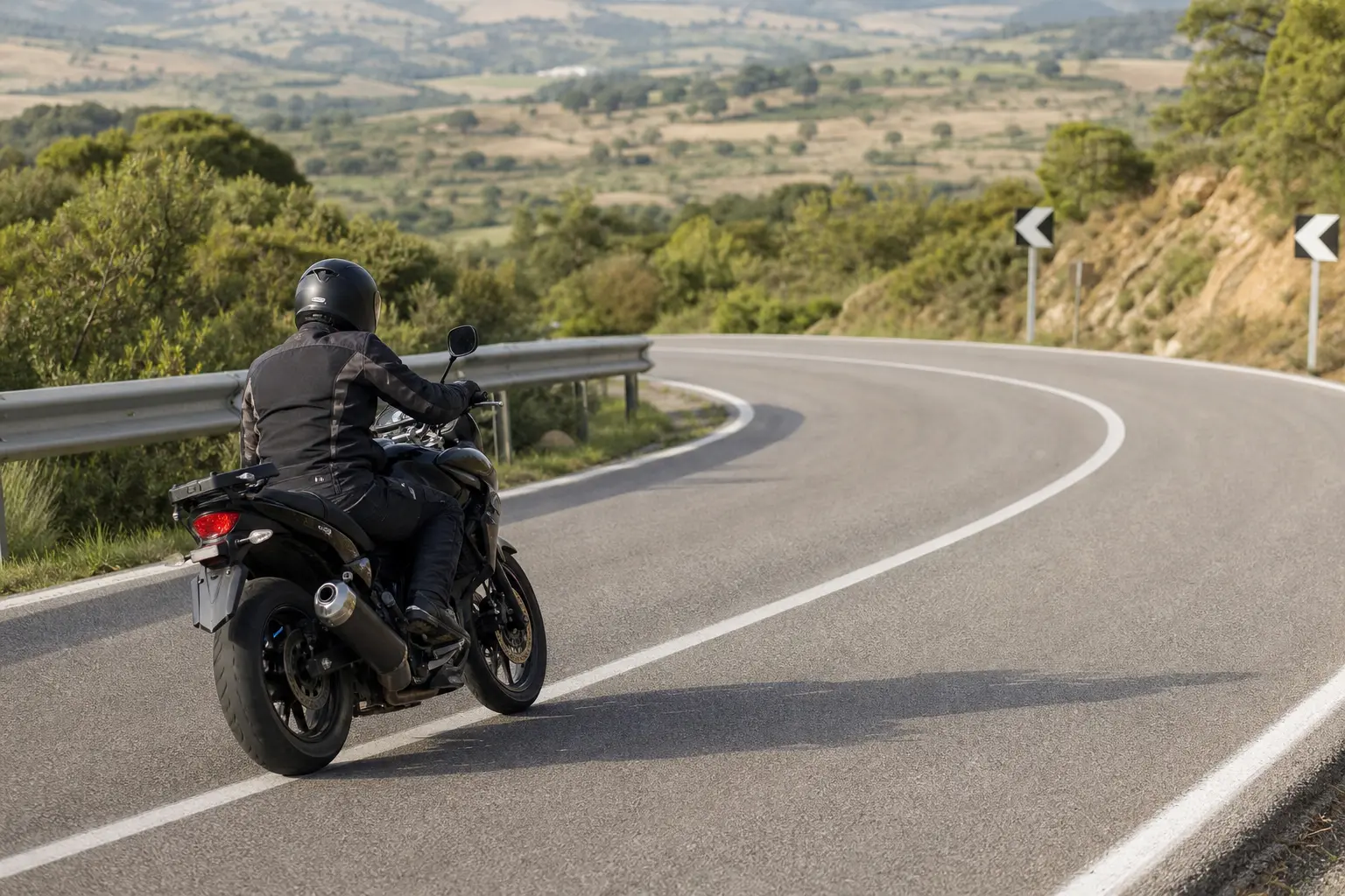 Motorcyclist approaching a broad rural curve with clear space ahead
