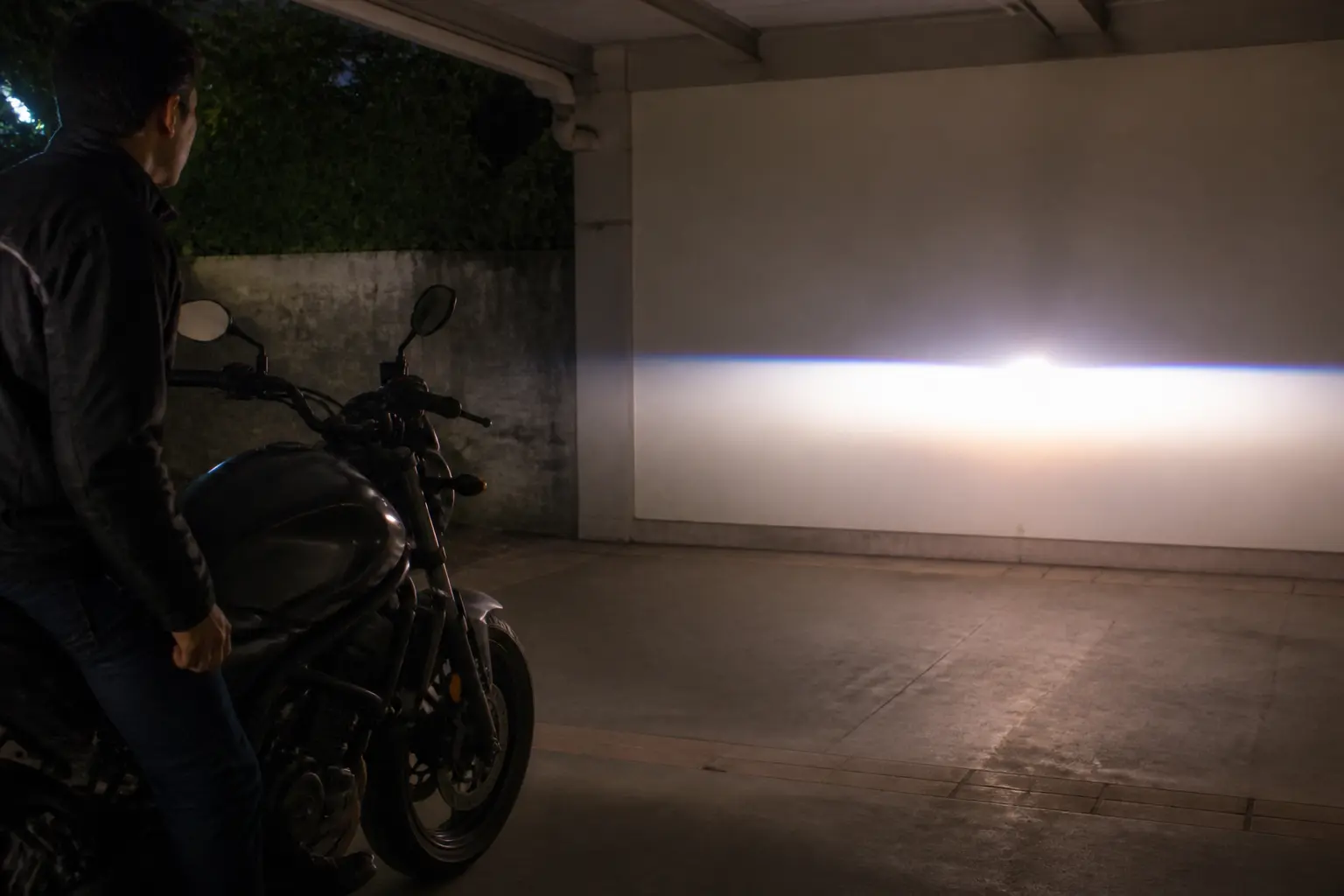 Rider observing motorcycle headlight beam in a controlled parked setting
