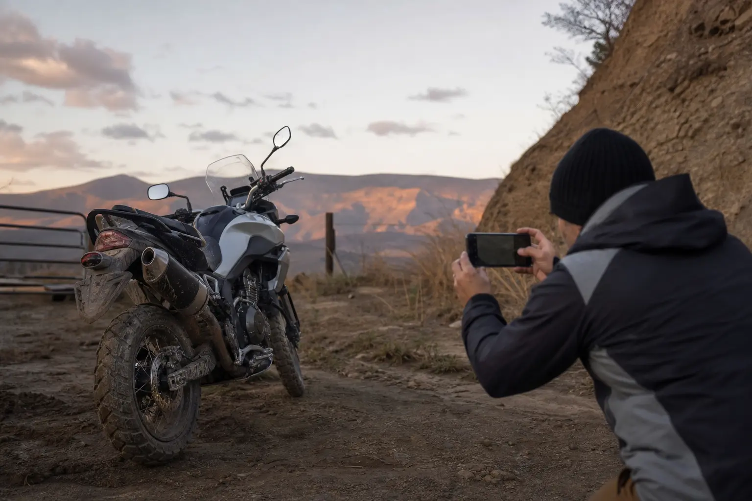 Rider documenting a parked motorcycle rear wheel after an off-road ride.