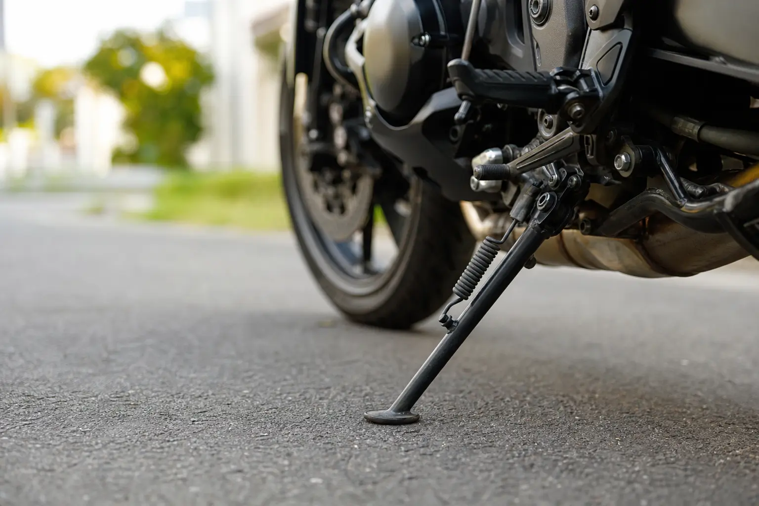 Motorcycle side stand resting securely on firm pavement.