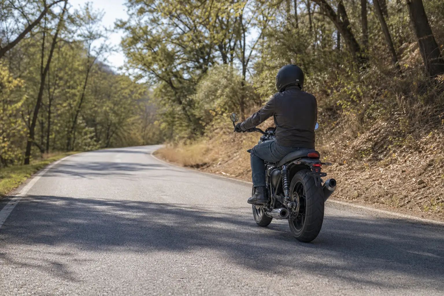 Motorcyclist on a quiet daytime local road during a conservative first return ride.